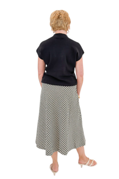 Back view of woman wearing Swagger Boutique’s Black Shirred Cap Sleeve Sweater with Black &amp; White Plaid Midi Skirt against white studio background.