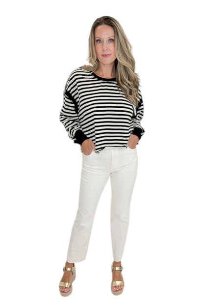 Front view of woman wearing Swagger Boutique’s Black &amp; White Striped Cut Out Back Sweatshirt with jeans against white studio background.