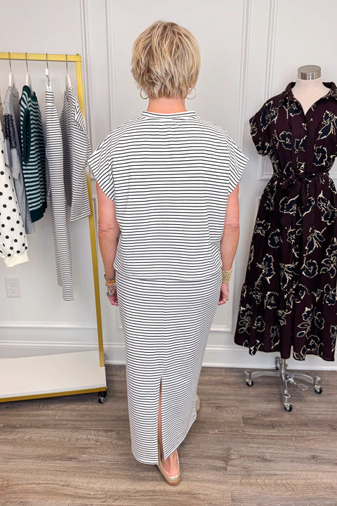 Back view of woman wearing Swagger Boutique’s Black &amp; White Striped Knit Skirt Top with clothing hanging in the background.