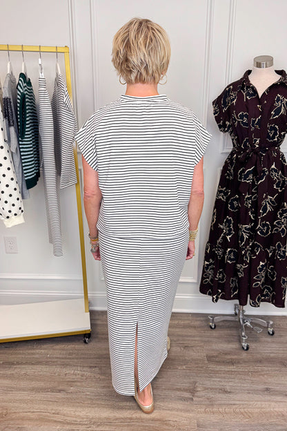 Back view of woman wearing Swagger Boutique’s Black &amp; White Striped Knit Skirt Top with clothing hanging in the background.