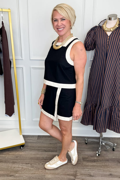 Side view of woman wearing Swagger Boutique’s Black &amp; White Wrap Skort &amp;  Square Neck Tank by Entro against white studio background. 
