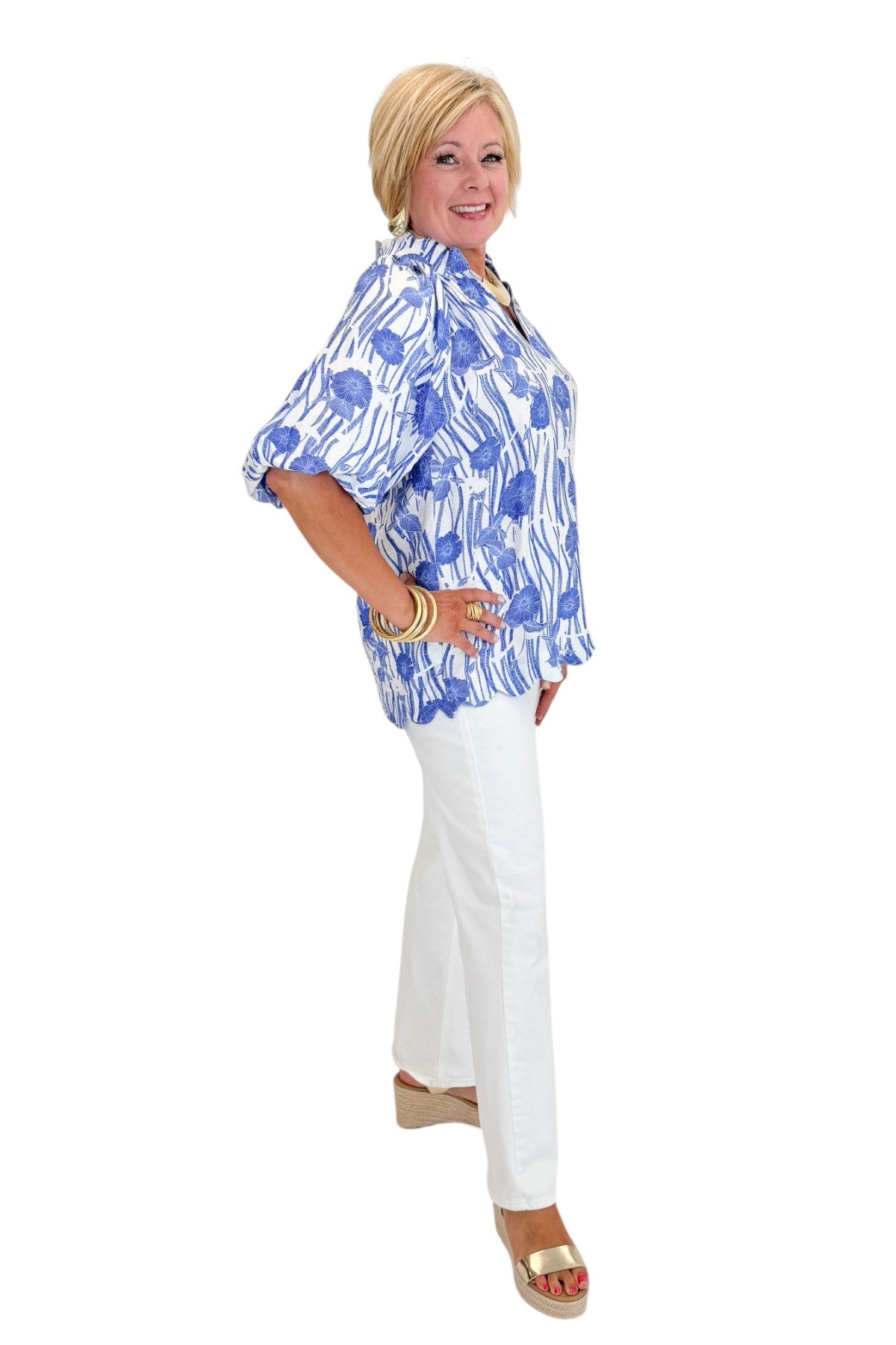 Side view of woman wearing Swagger Boutique’s Blue Floral Puff Sleeve Top with jeans against white studio background.