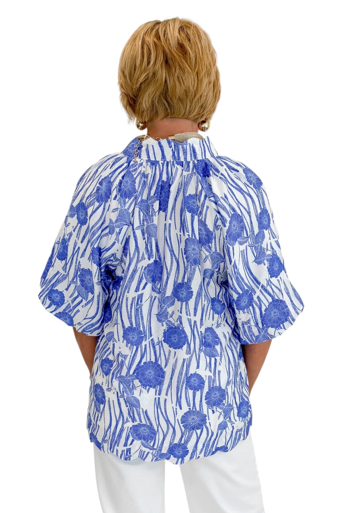 Back view of woman wearing Swagger Boutique’s Blue Floral Puff Sleeve Top with jeans against white studio background.