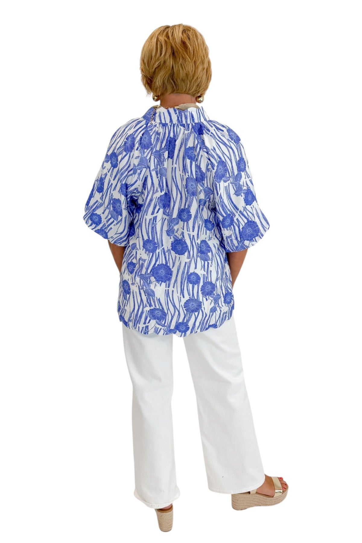 Back view of woman wearing Swagger Boutique’s Blue Floral Puff Sleeve Top with jeans against white studio background.