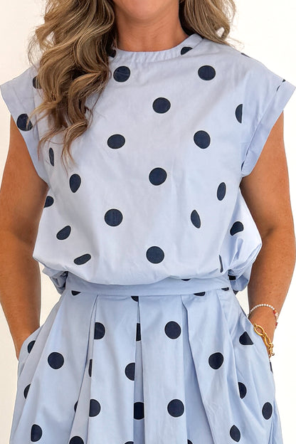 Front detail view of woman wearing Swagger Boutique’s Blue Polka Dot Bubble Hem Tank with matching Blue Polka Dot Pleated Midi Skirt against white studio background.