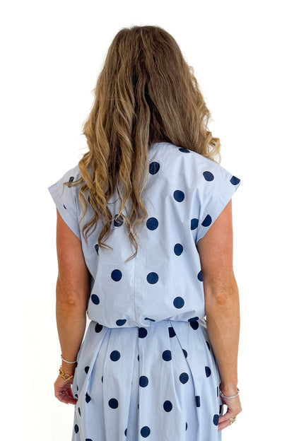 Back view of woman wearing Swagger Boutique’s Blue Polka Dot Bubble Hem Tank with matching Blue Polka Dot Pleated Midi Skirt against white studio background.