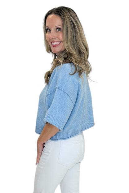 Side view of woman wearing Swagger Boutique’s Blue Ribbed Detail Short Sleeve Sweater with jeans against white studio background.
