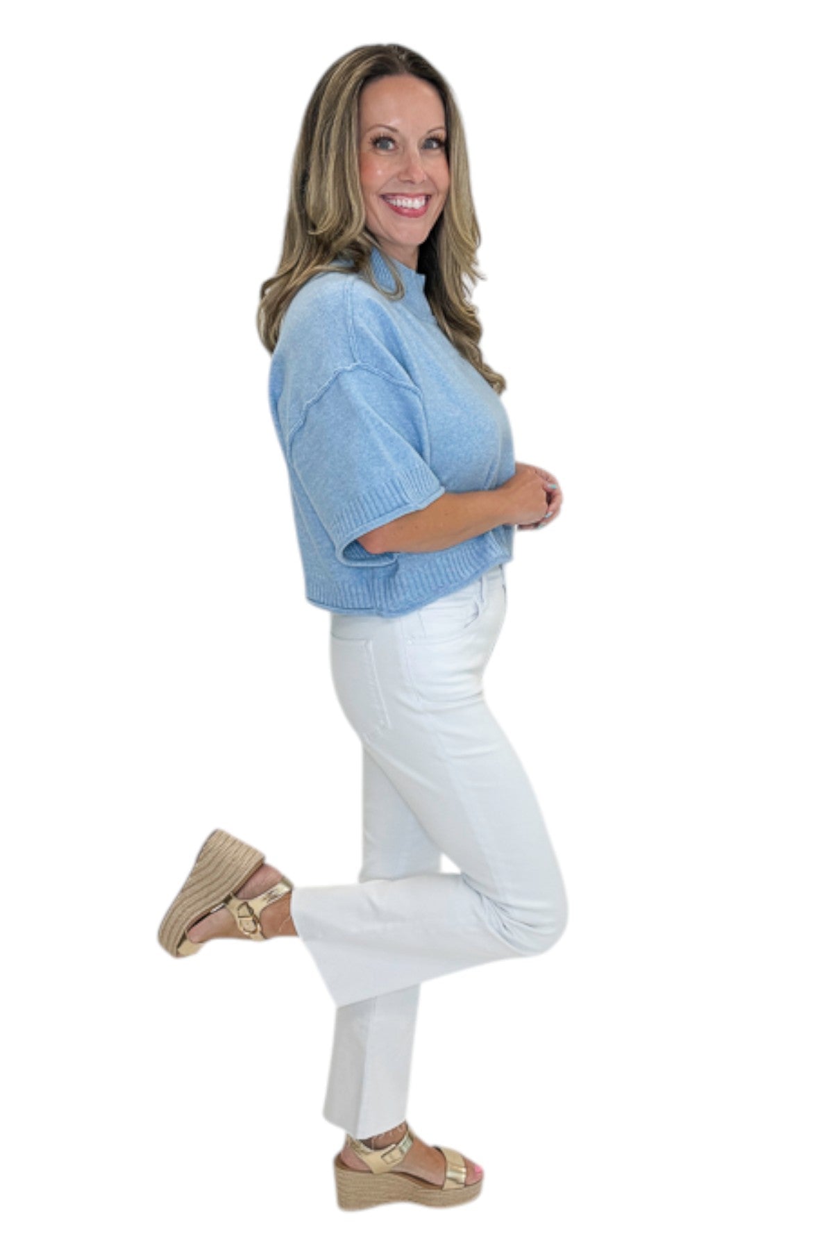 Side view of woman wearing Swagger Boutique’s Blue Ribbed Detail Short Sleeve Sweater with jeans against white studio background.