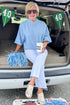 Front view of woman wearing Swagger Boutique’s Blue Ribbed Detail Short Sleeve Sweater with jeans sitting on a tailgate.
