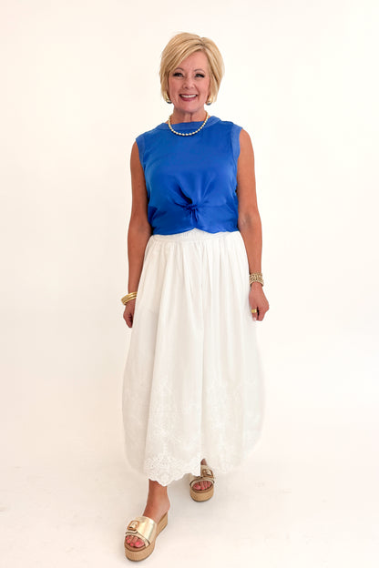 Front view of woman wearing Swagger Boutique’s Blue Sleeveless Tank With Twist by Skies Are Blue with White Embroidered Skirt against white studio background.