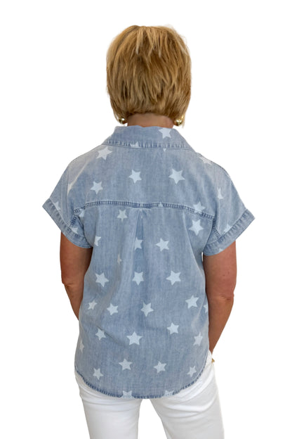 Back view of woman wearing Swagger Boutique’s Spark After Dark Blue Star Print Denim Top with jeans against white studio background.