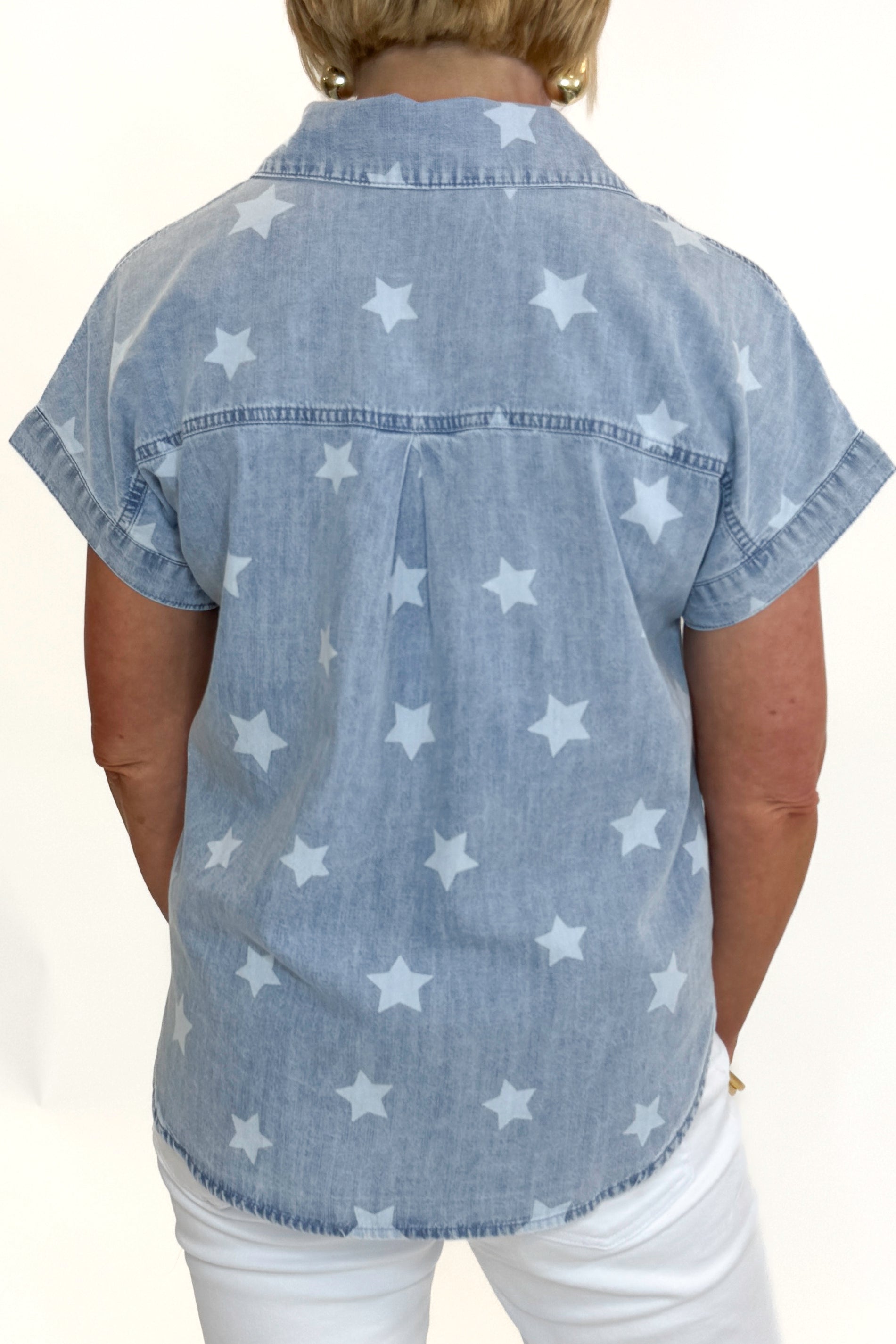 Back view of woman wearing Swagger Boutique’s Spark After Dark Blue Star Print Denim Top with jeans against white studio background.