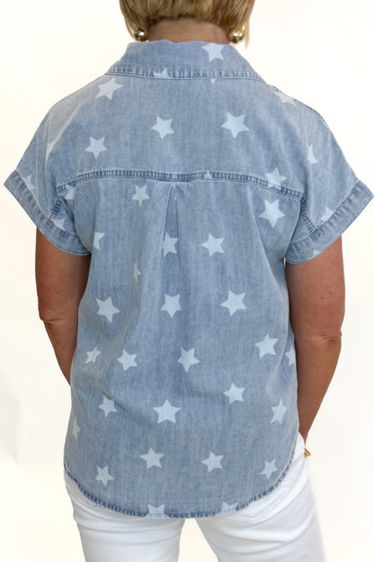 Back view of woman wearing Swagger Boutique’s Spark After Dark Blue Star Print Denim Top with jeans against white studio background.