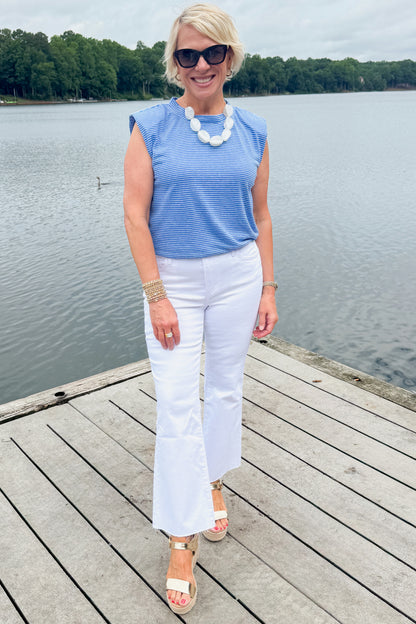 Front view of woman wearing Swagger Boutique’s Blue Striped Bubble Hem Sleeveless Top with jeans standing on a dock outside.