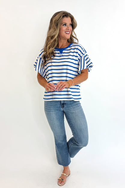 Front view of woman wearing Swagger Boutique’s Striped Flutter Sleeve Terry Top with jeans against white studio background.