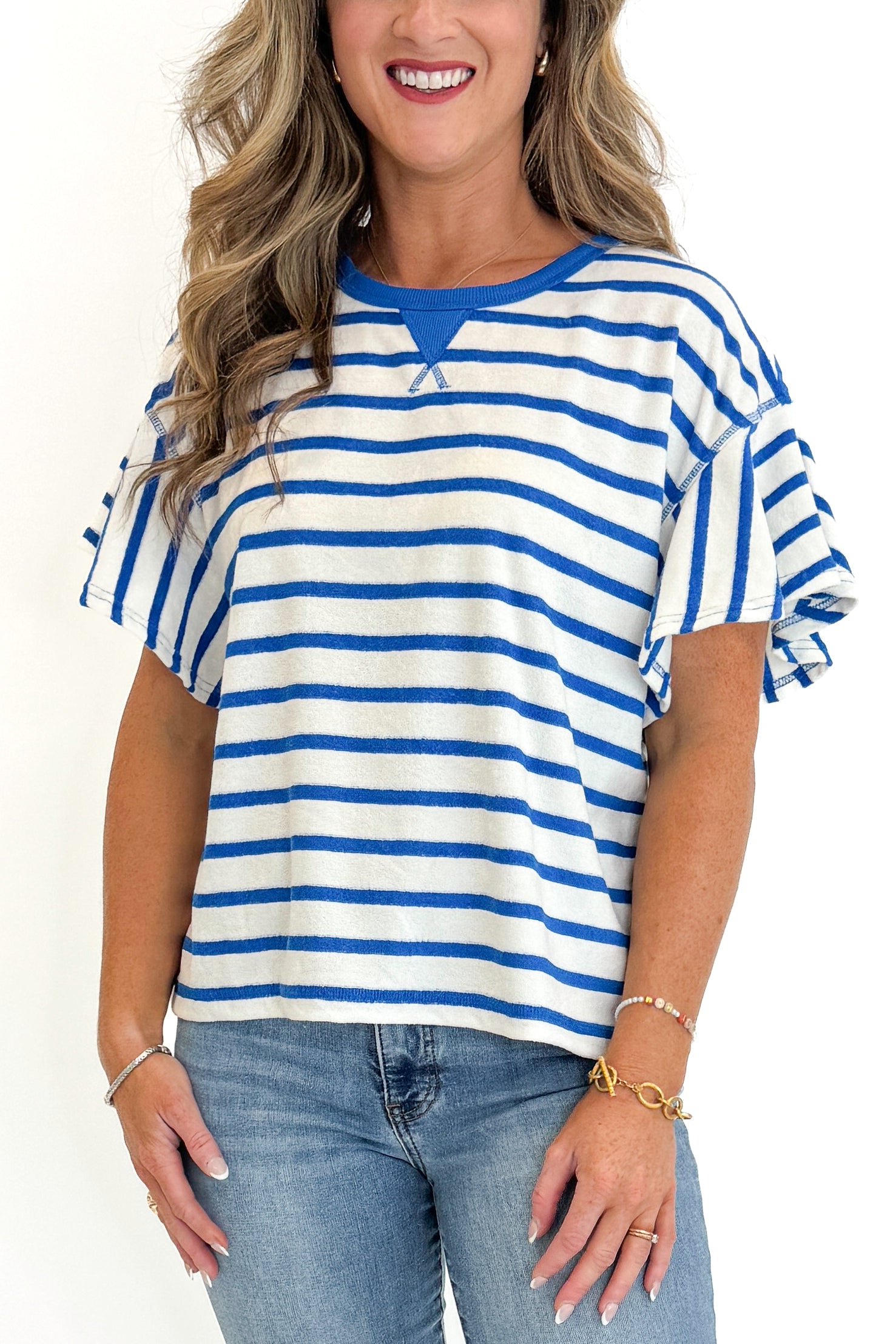 Front detail view of woman wearing Swagger Boutique’s Striped Flutter Sleeve Terry Top with jeans against white studio background.