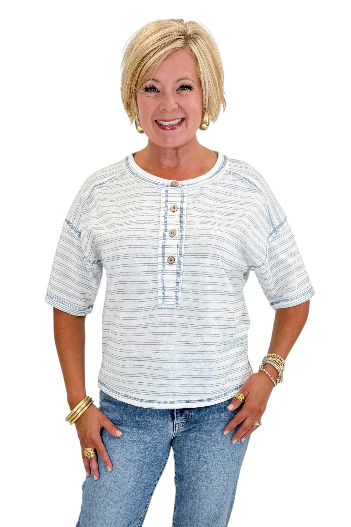 Front view of woman wearing Swagger Boutique’s Blue Striped Relaxed Fit Top with jeans against white studio background.
