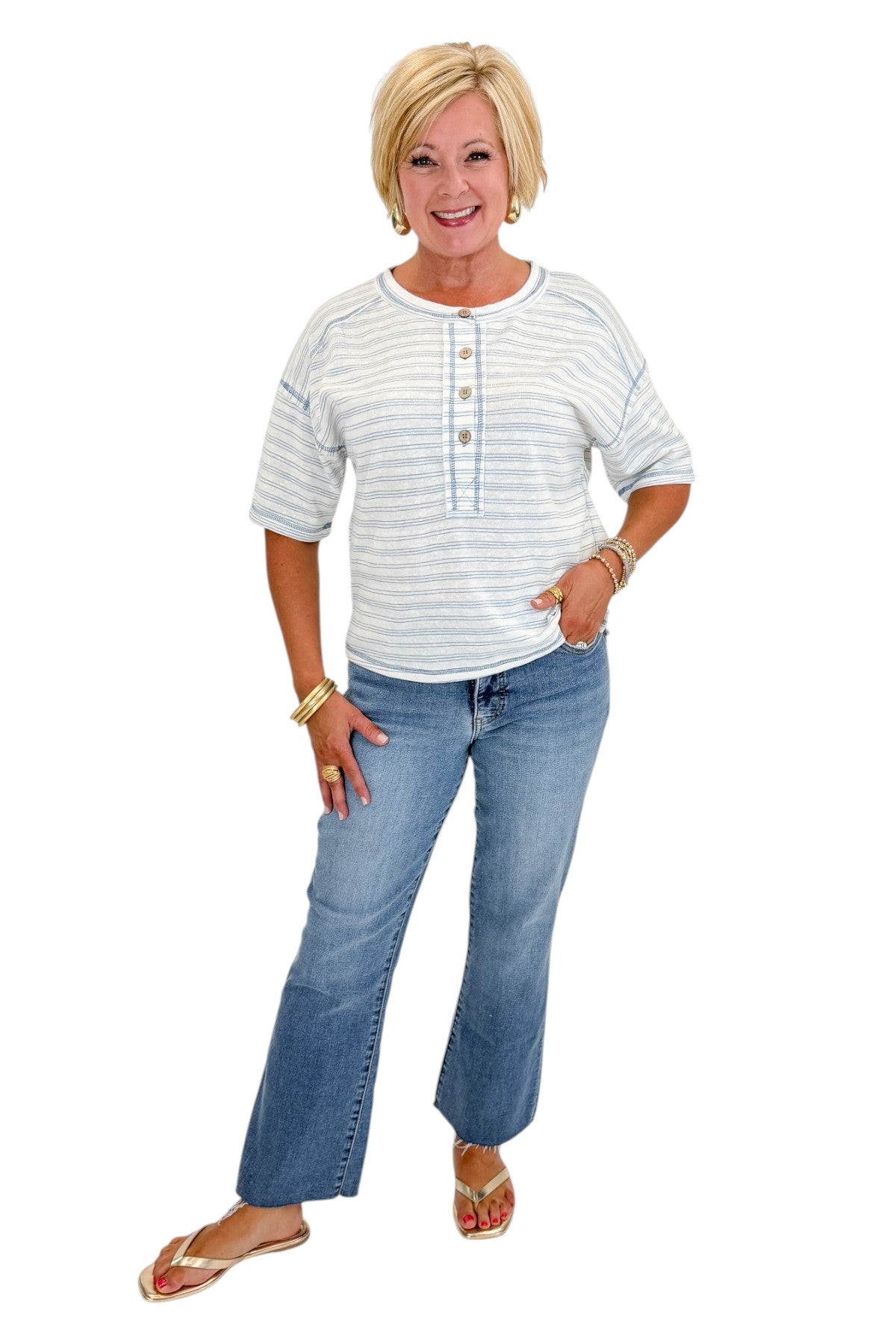 Front view of woman wearing Swagger Boutique’s Blue Striped Relaxed Fit Top with jeans against white studio background.