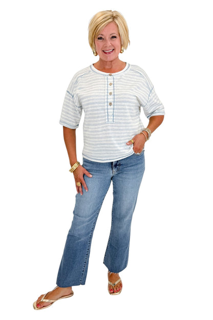 Front view of woman wearing Swagger Boutique’s Blue Striped Relaxed Fit Top with jeans against white studio background.