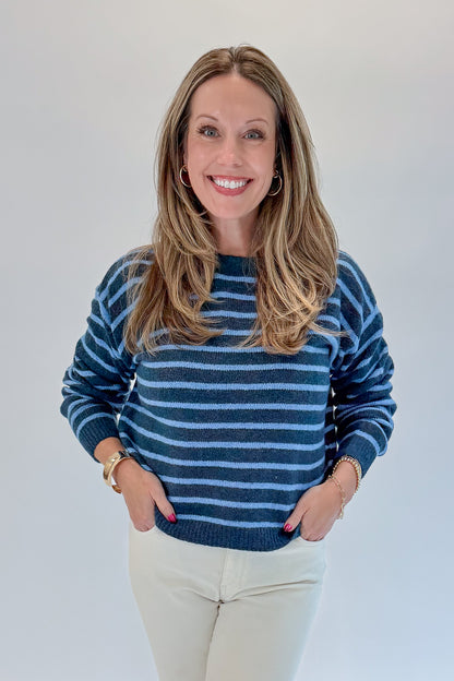 Front view of woman wearing Swagger Boutique’s Blue Striped Sweater with jeans against white studio background.