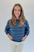 Front view of woman wearing Swagger Boutique’s Blue Striped Sweater with jeans against white studio background.