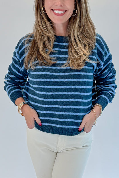 Front detail view of woman wearing Swagger Boutique’s Blue Striped Sweater with jeans against white studio background.