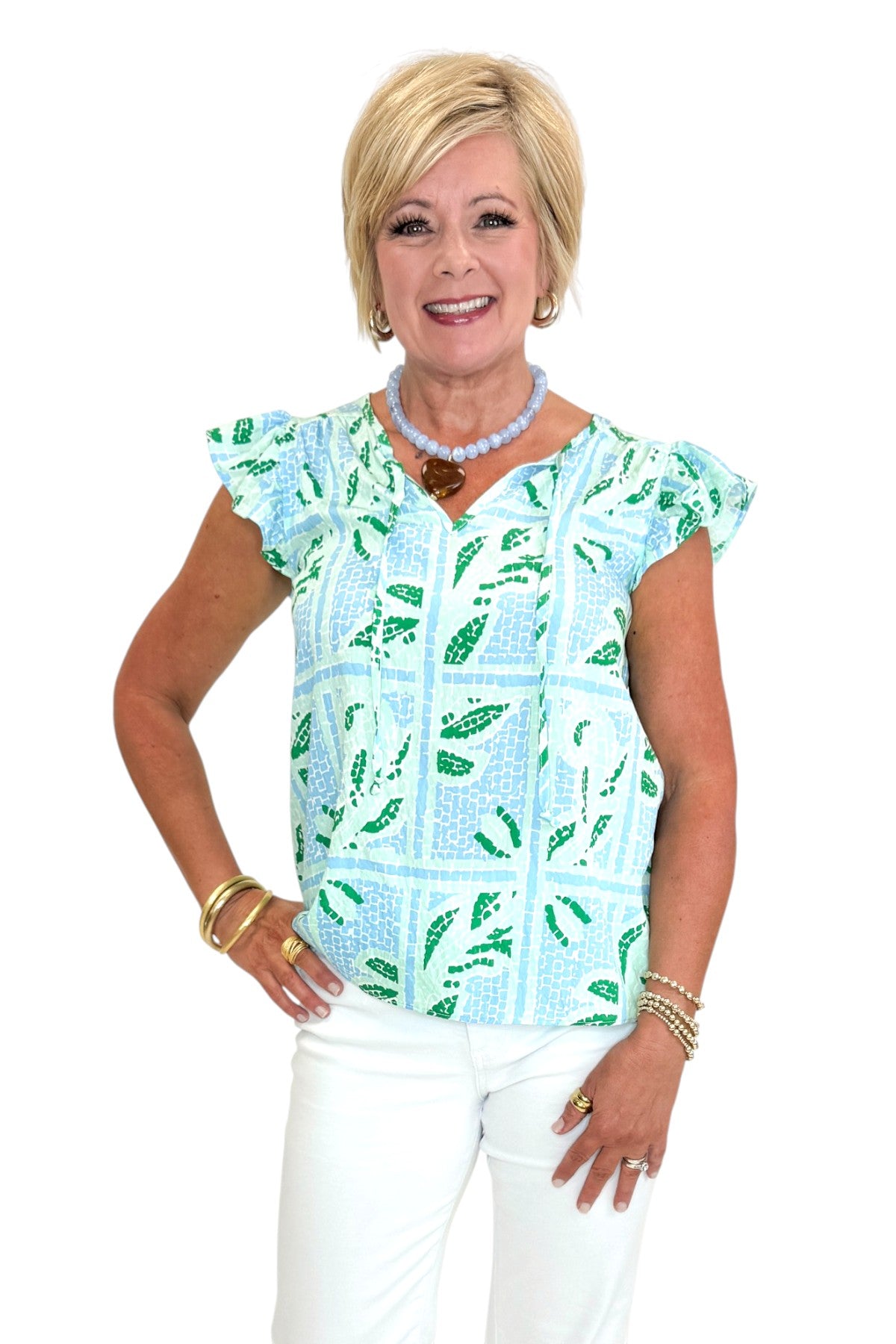 Front view of woman wearing Swagger Boutique’s Blue Tile Print Lydia Top by Mary Square with jeans against white studio background.