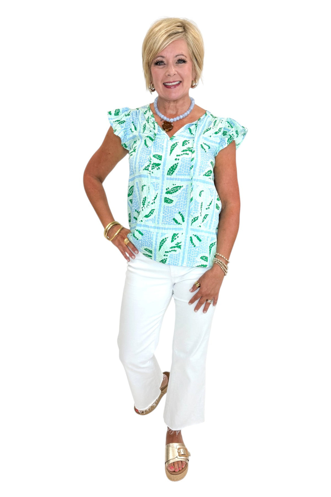 Front view of woman wearing Swagger Boutique’s Blue Tile Print Lydia Top by Mary Square with jeans against white studio background.