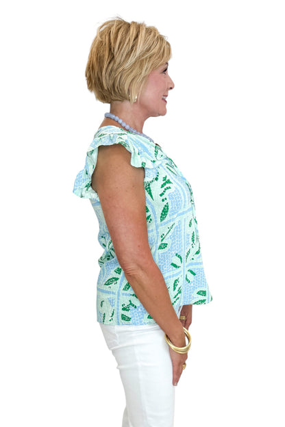 Side view of woman wearing Swagger Boutique’s Blue Tile Print Lydia Top by Mary Square with jeans against white studio background.