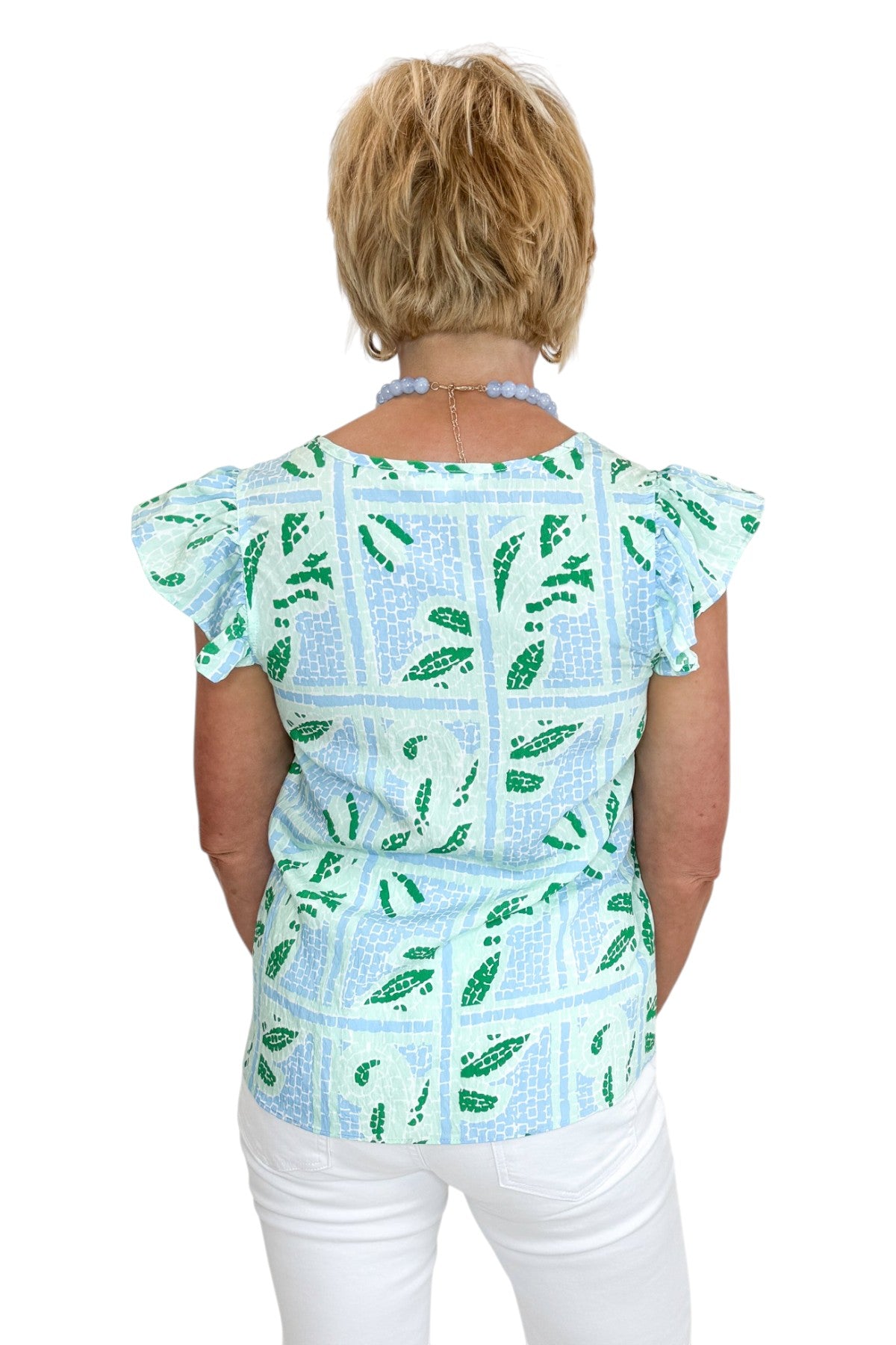 Back view of woman wearing Swagger Boutique’s Blue Tile Print Lydia Top by Mary Square with jeans against white studio background.