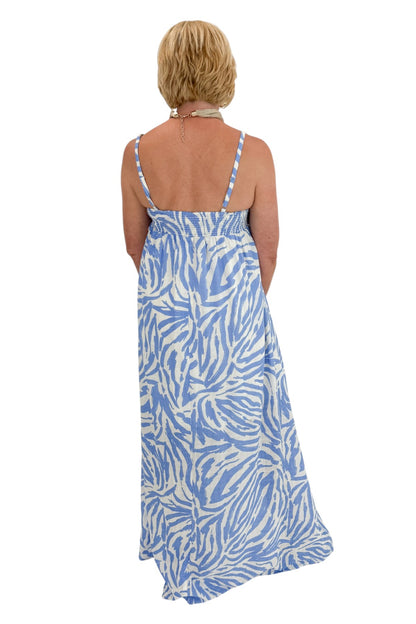 Back view of woman wearing Swagger Boutique’s Blue &amp; Cream Animal Print Maxi Dress by Entro with sandals against white studio background.
