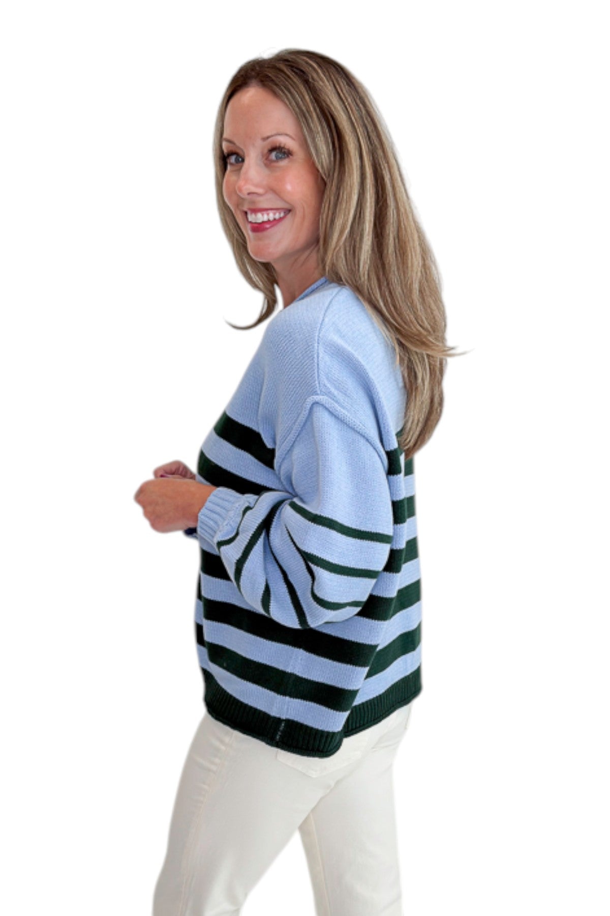 Side view of woman wearing Swagger Boutique’s Blue &amp; Green Striped Sweater with jeans against white studio background.
