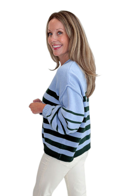 Side view of woman wearing Swagger Boutique’s Blue &amp; Green Striped Sweater with jeans against white studio background.