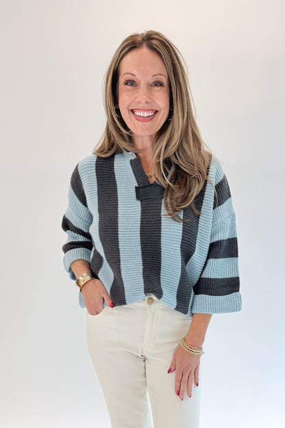 Front view of woman wearing Swagger Boutique’s Blue &amp; Grey Striped 3/4 Sleeve Sweater with jeans against white studio background.