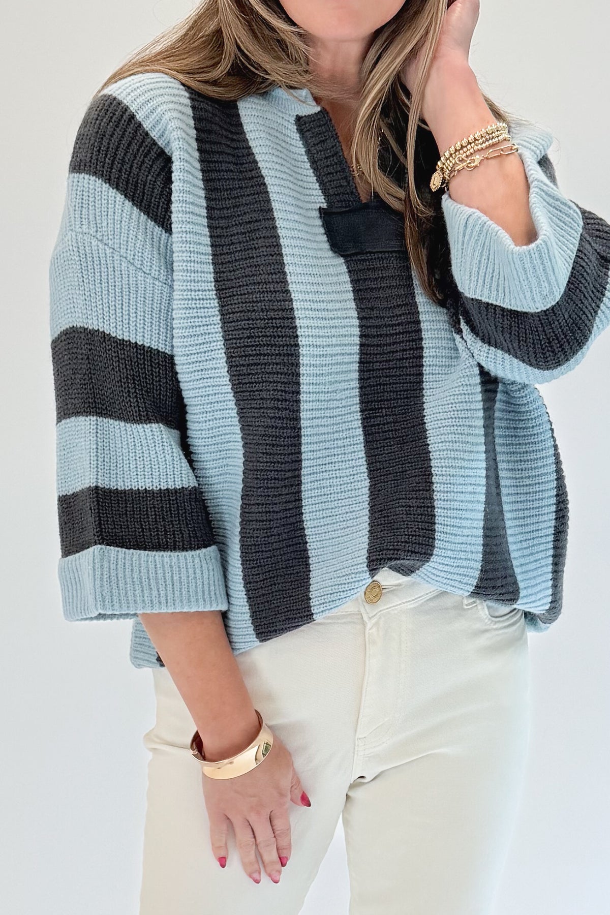 Front detail view of woman wearing Swagger Boutique’s Blue &amp; Grey Striped 3/4 Sleeve Sweater with jeans against white studio background.