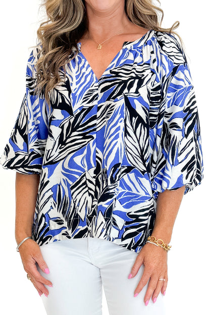 Front detail view of woman wearing Swagger Boutique’s Blue &amp; Navy Tropical Printed 3/4 Sleeve Top with jeans against white studio background.