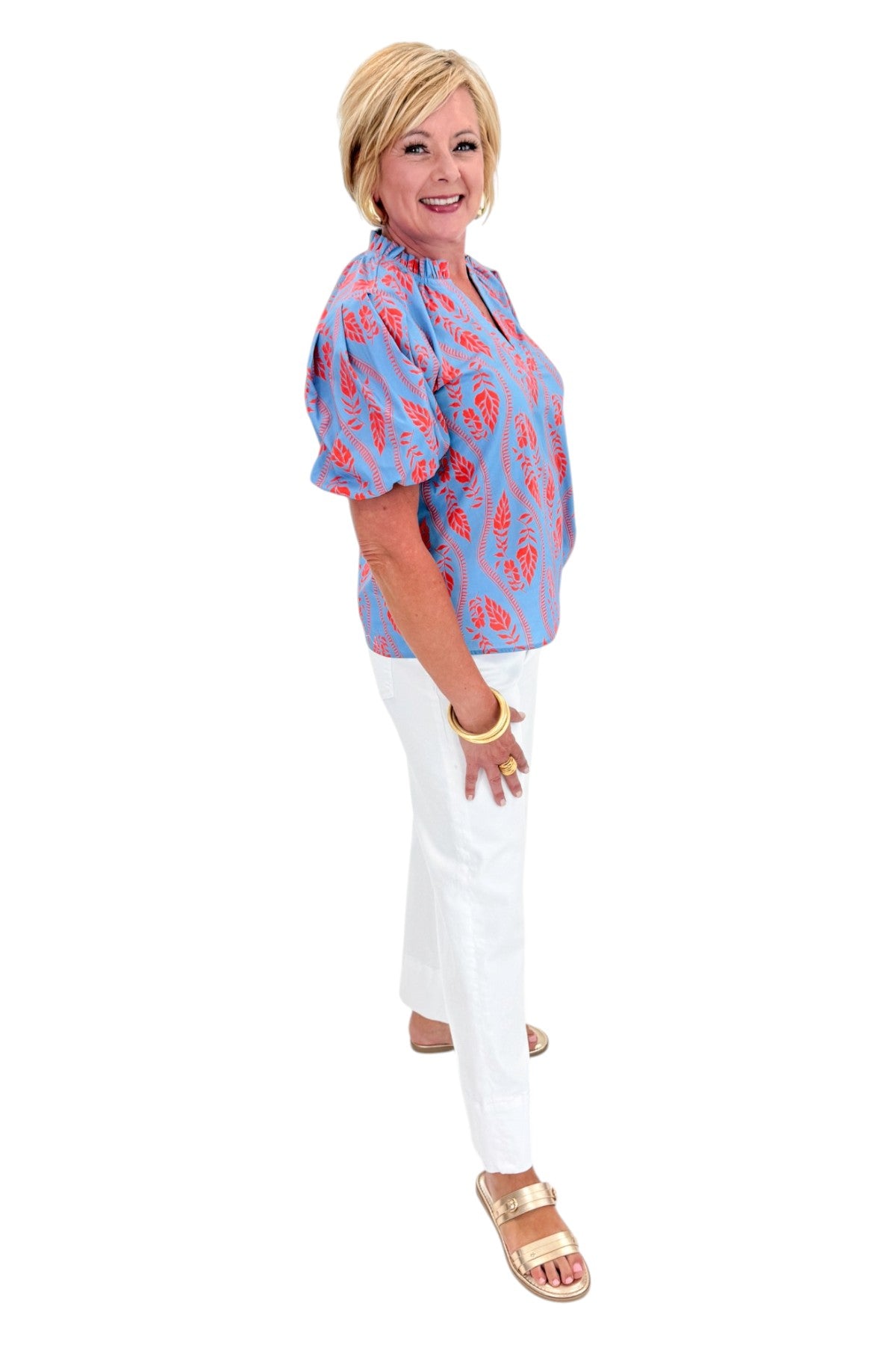 Side view of woman wearing Swagger Boutique’s Blue &amp; Orange Botanical Print Short Sleeve Top with jeans against white studio background.