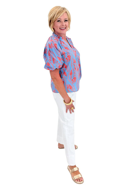 Side view of woman wearing Swagger Boutique’s Blue &amp; Orange Botanical Print Short Sleeve Top with jeans against white studio background.
