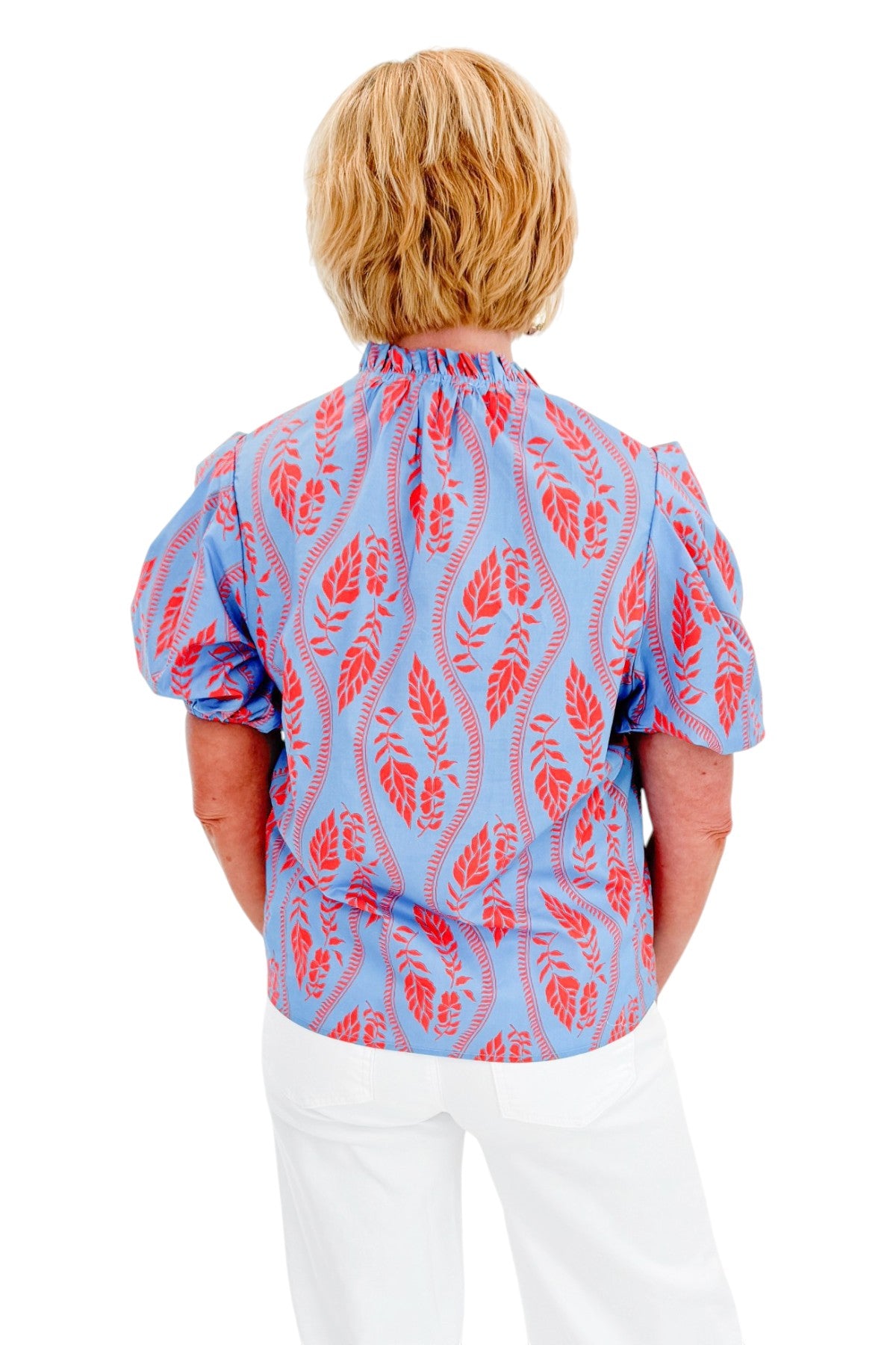 Back view of woman wearing Swagger Boutique’s Blue &amp; Orange Botanical Print Short Sleeve Top with jeans against white studio background.