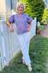 Front view of woman wearing Swagger Boutique’s Blue & Orange Botanical Print Short Sleeve Top with jeans standing outside in a yard.