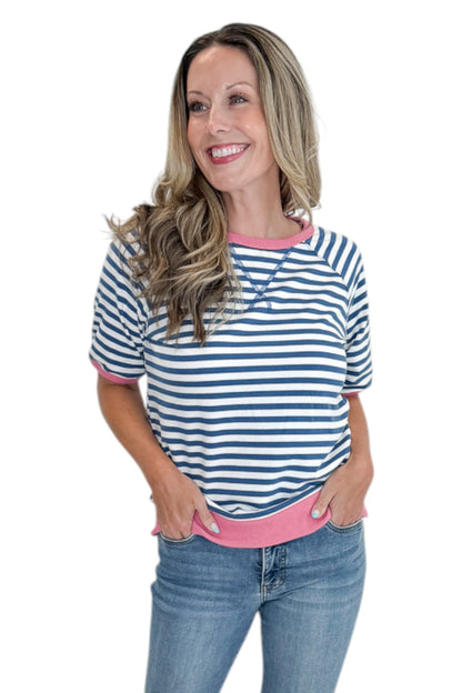 Front view of woman wearing Swagger Boutique’s Blue &amp; Pink Striped Short Sleeve Sweatshirt with jeans against white studio background.
