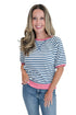 Front view of woman wearing Swagger Boutique’s Blue & Pink Striped Short Sleeve Sweatshirt with jeans against white studio background.