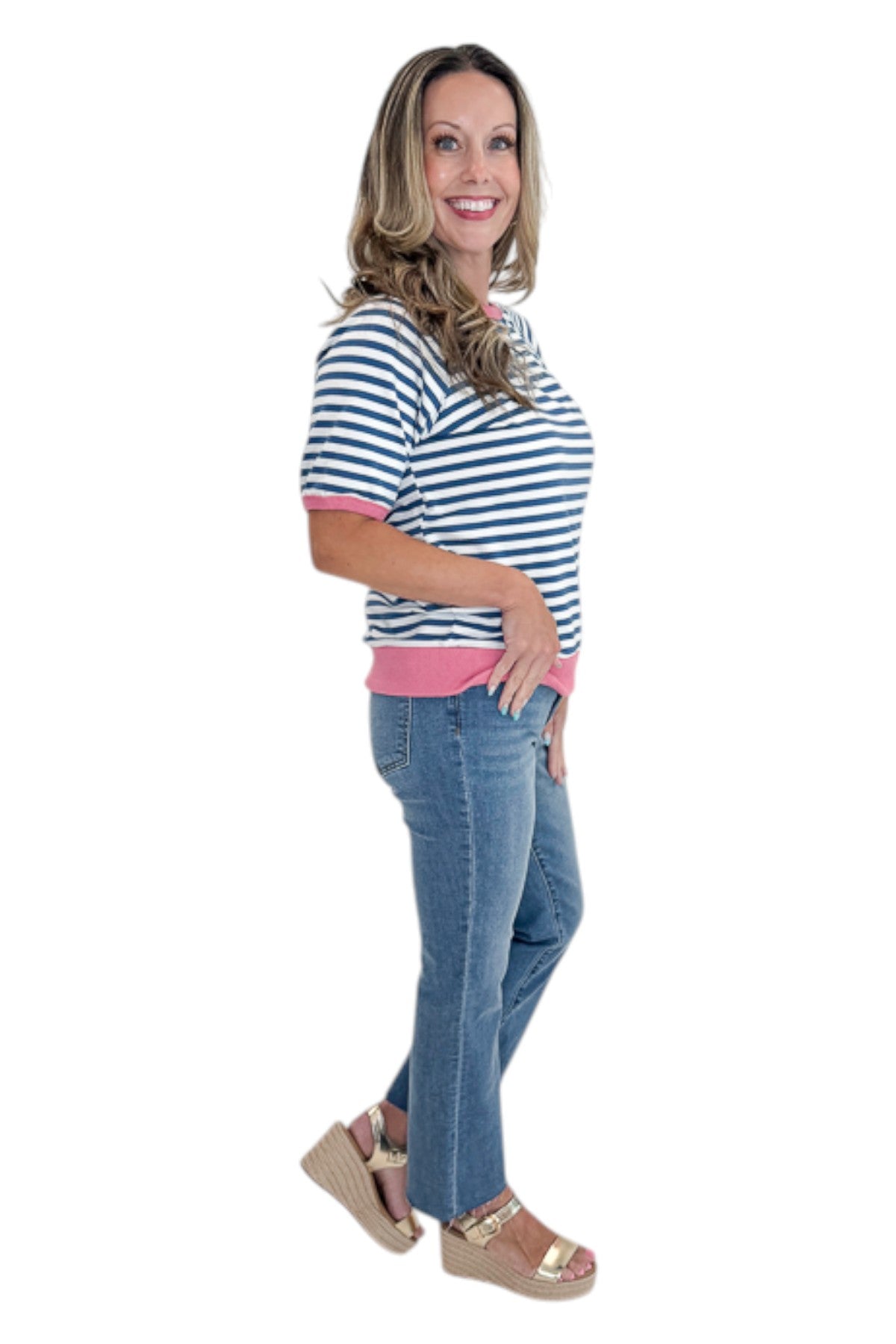 Side view of woman wearing Swagger Boutique’s Blue &amp; Pink Striped Short Sleeve Sweatshirt with jeans against white studio background.