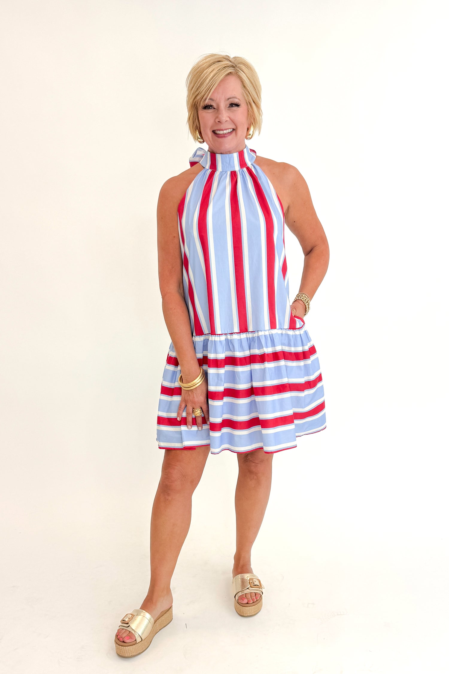 Front view of woman wearing Swagger Boutique’s Blue &amp; Red Striped Halter Neck Dress by Entro with sandals against white studio background.