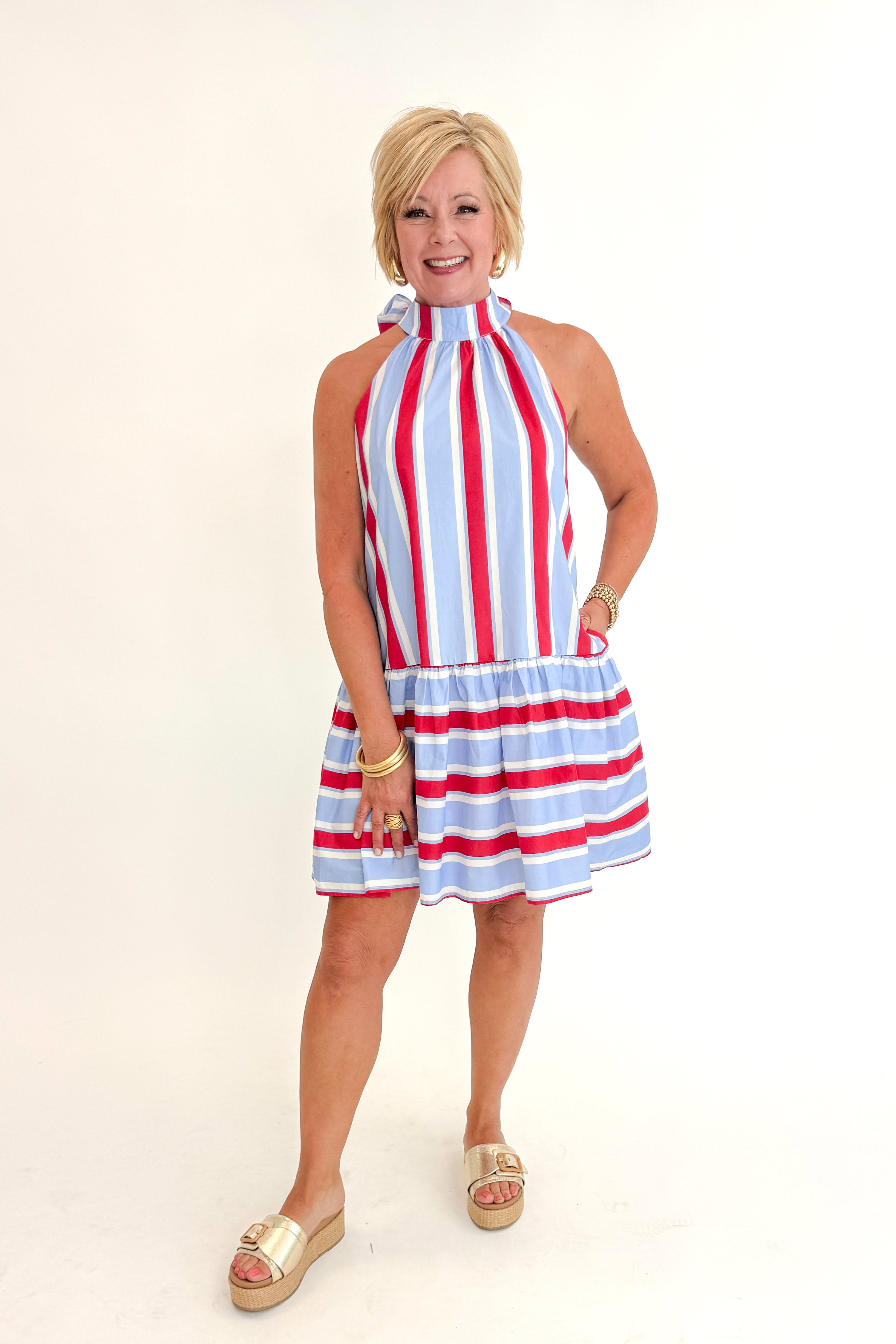 Front view of woman wearing Swagger Boutique’s Blue &amp; Red Striped Halter Neck Dress by Entro with sandals against white studio background.