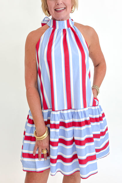 Front detail view of woman wearing Swagger Boutique’s Blue &amp; Red Striped Halter Neck Dress by Entro with sandals against white studio background.
