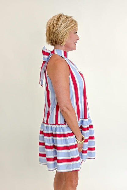 Side view of woman wearing Swagger Boutique’s Blue &amp; Red Striped Halter Neck Dress by Entro with sandals against white studio background.