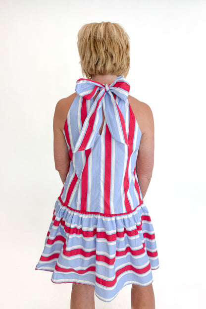 Back view of woman wearing Swagger Boutique’s Blue &amp; Red Striped Halter Neck Dress by Entro with sandals against white studio background.