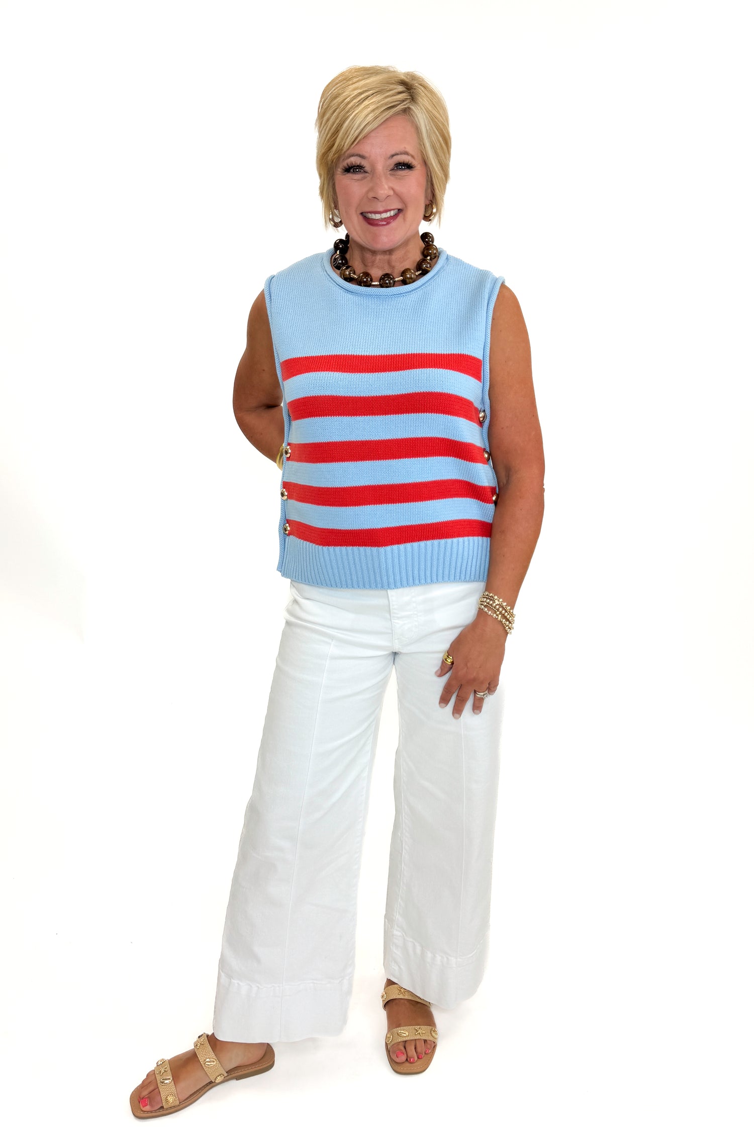 Front view of woman wearing Swagger Boutique’s Blue &amp; Red Striped Sleeveless Sweater by Entro with jeans against white studio background.