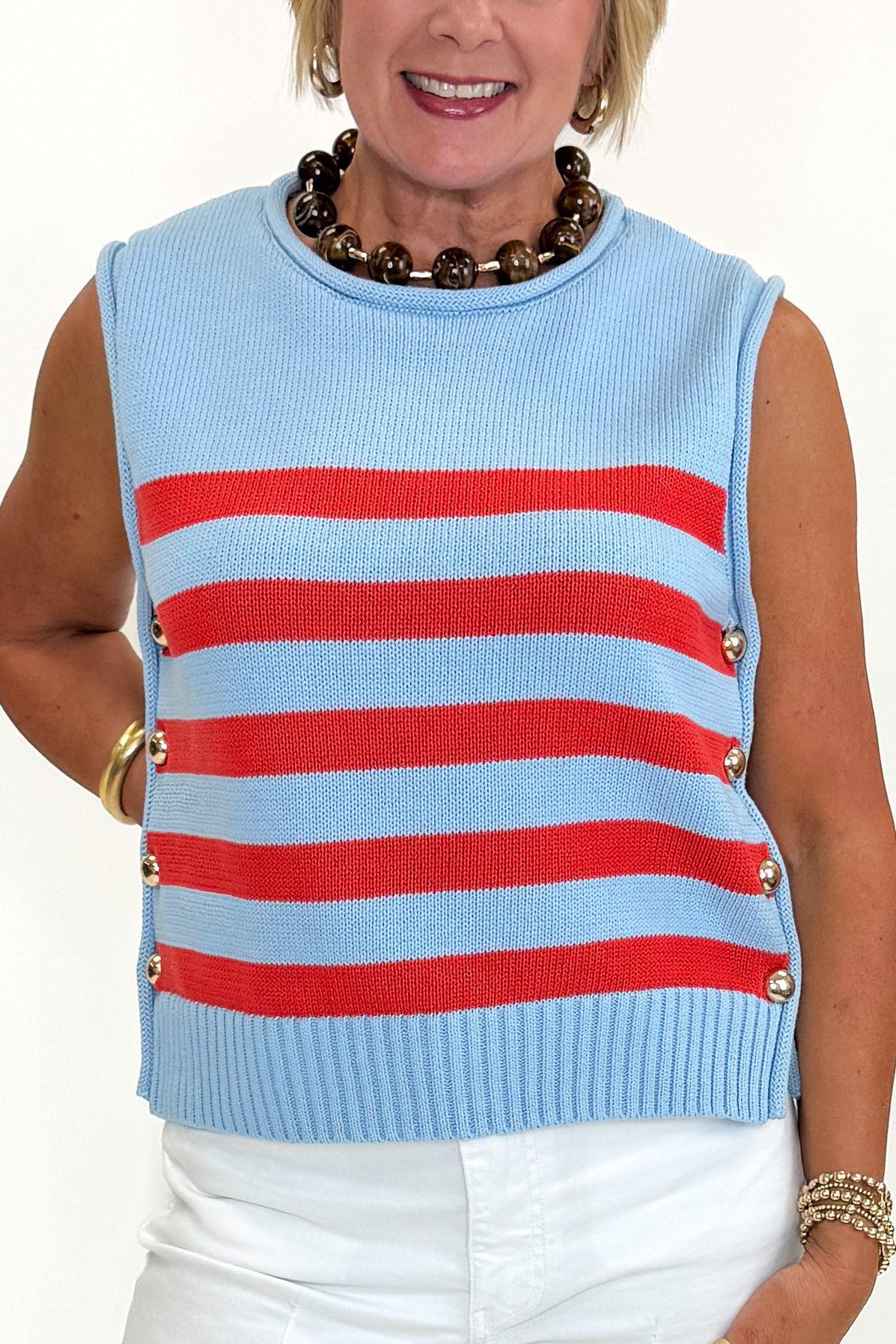 Front detail view of woman wearing Swagger Boutique’s Blue &amp; Red Striped Sleeveless Sweater by Entro with jeans against white studio background.